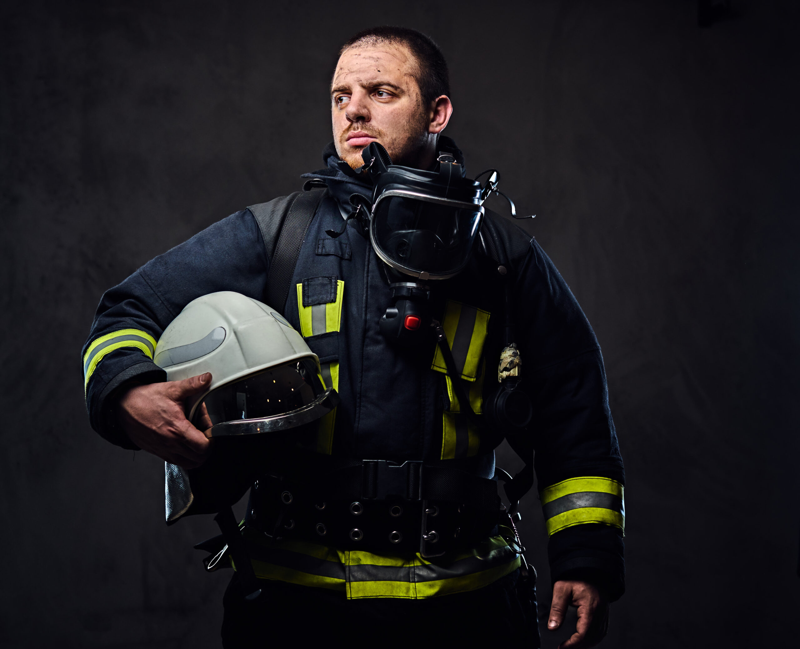 Weary firefighter holding helmet, embodying addiction struggle among first responders.