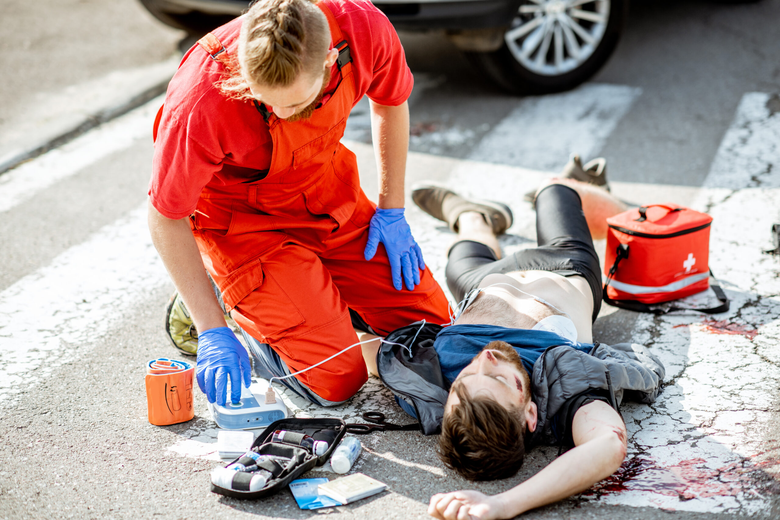 A first responder, in full uniform, diligently cares for an injured man on the roadside, exemplifying the high-stress scenarios that contribute to mental health challenges in emergency personnel.