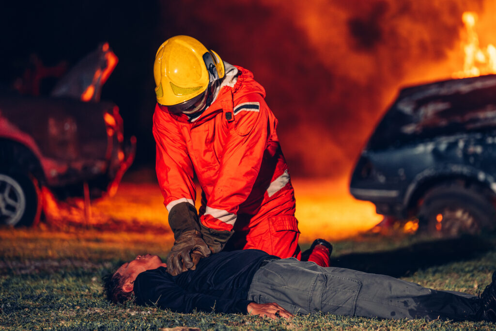 A firefighter performs CPR on a victim of a car crash, highlighting the secondary trauma and mental health challenges faced by first responders who witness tragedy.