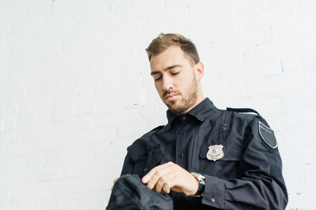 A police officer looking down, appearing distressed, representing the stigma surrounding mental health and the importance of confidential PTSD treatment for first responders.