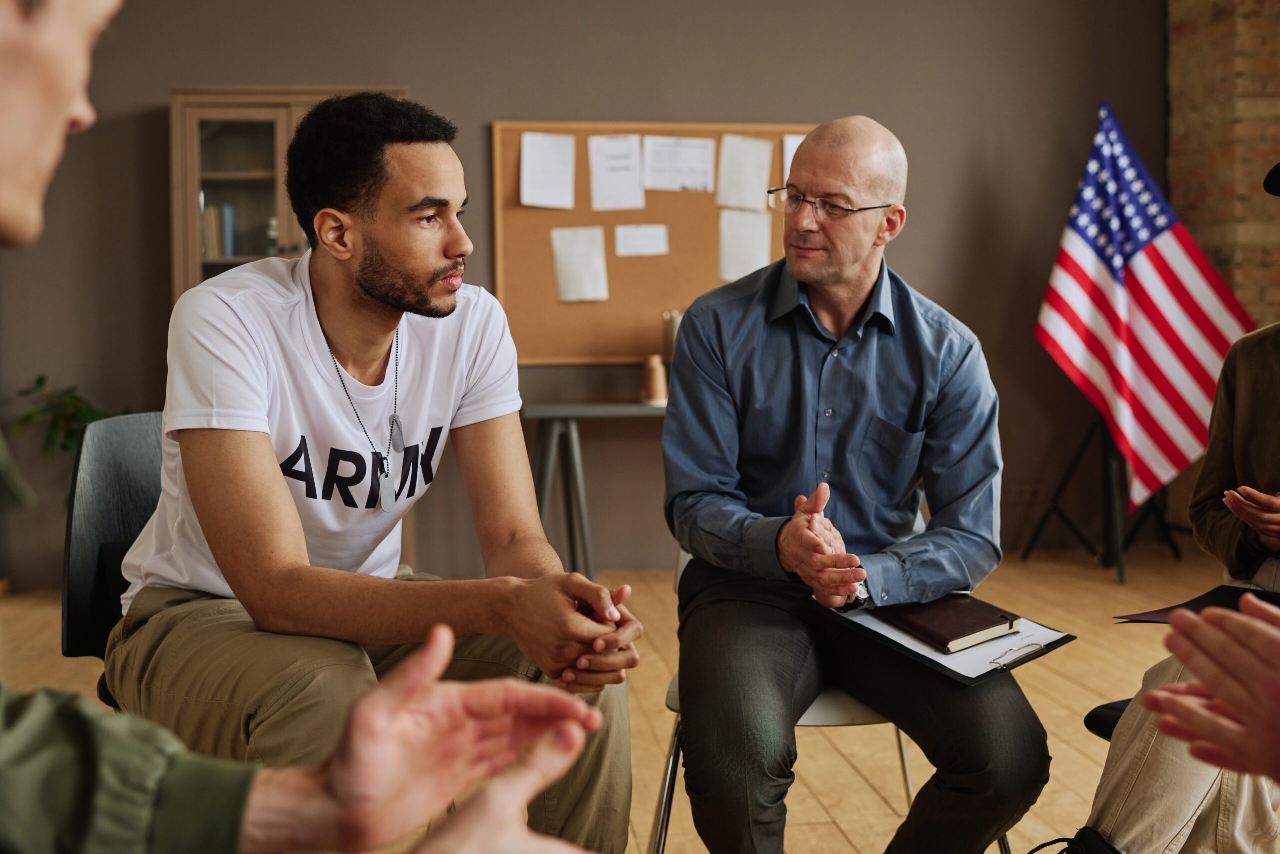 A military first responder participating in a therapy group session, discussing various types of therapy available for first responders to support mental health recovery.