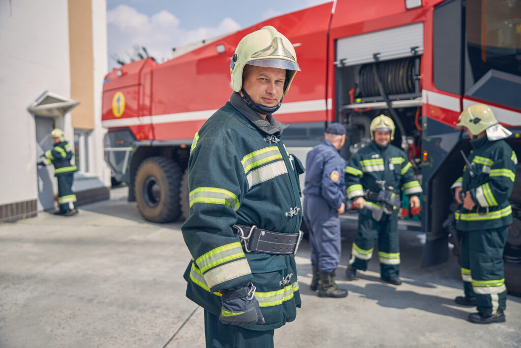 Group of firefighters in uniform, gathered in a supportive discussion, illustrating professional and peer support strategies.