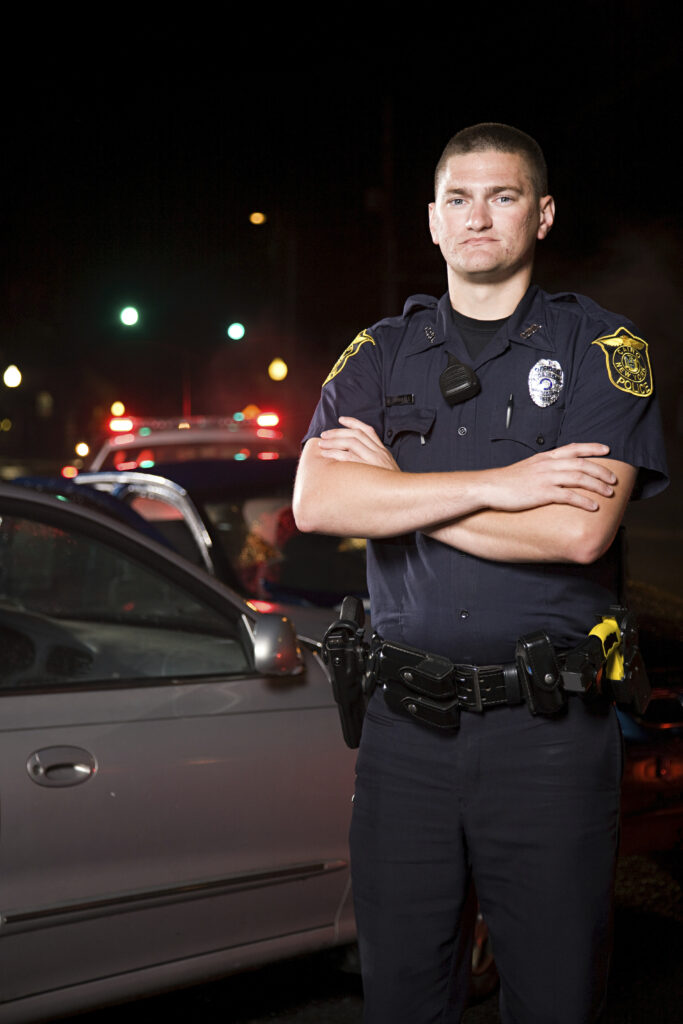 A police officer standing with arms crossed, symbolizing resilience and the importance of suicide prevention for first responders facing mental health challenges.