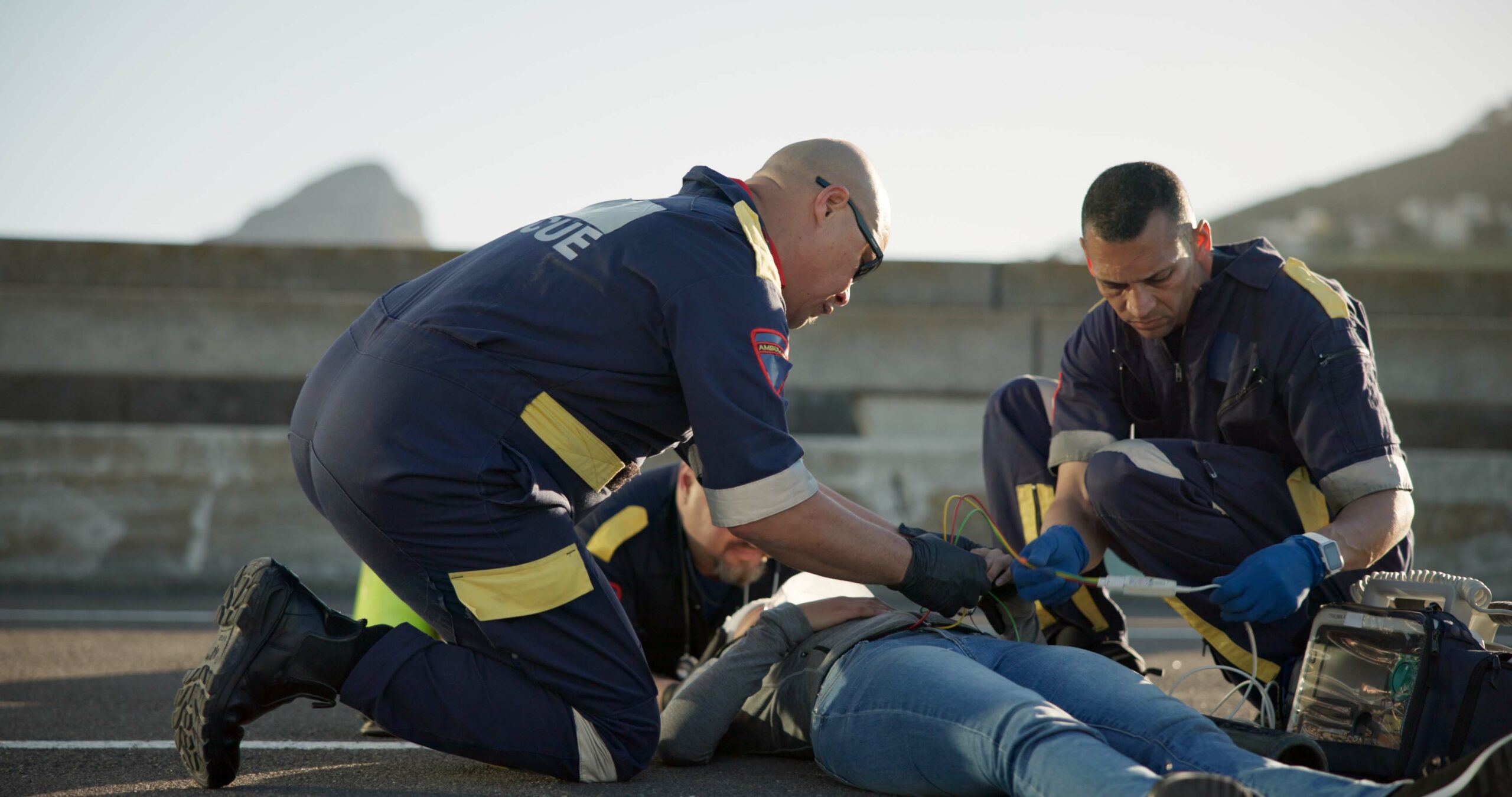 Paramedics assisting a person on the ground during a traumatic situation, symbolizing the need for confidential PTSD treatment for first responders.