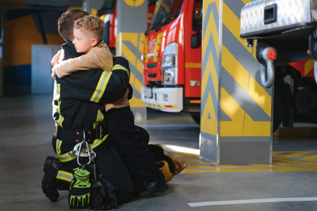 A firefighter embraces his son, showing the emotional toll of first responder PTSD and family impact.
