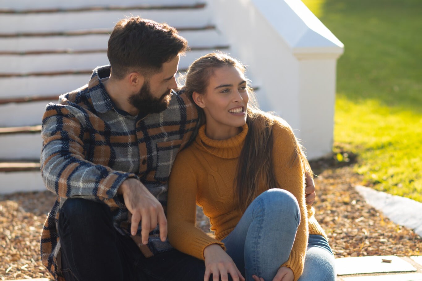 Couple sitting close together on the front steps of their home, talking. Supporting a first responder in recovery starts at home
